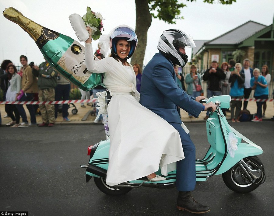 Just married: A recently married couple wave to the crowd from their mint coloured scooter 