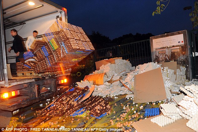 French egg producers throw crates of eggs from the back of a truck onto the sidewalk in front of the taxes and internal revenue service office 