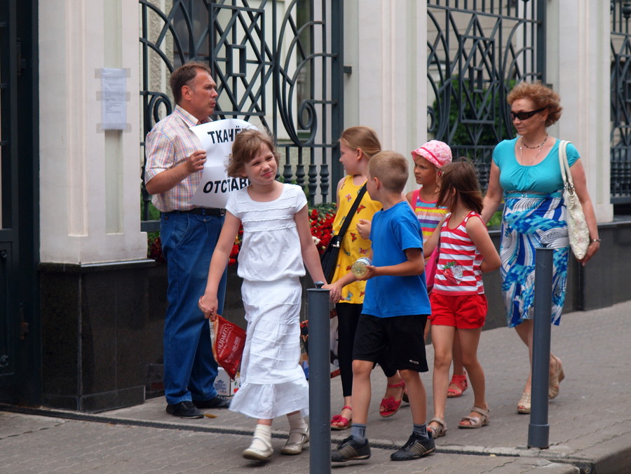 Дети идут мимо гражданского активиста  у Представительства Краснодарского края в Москве.