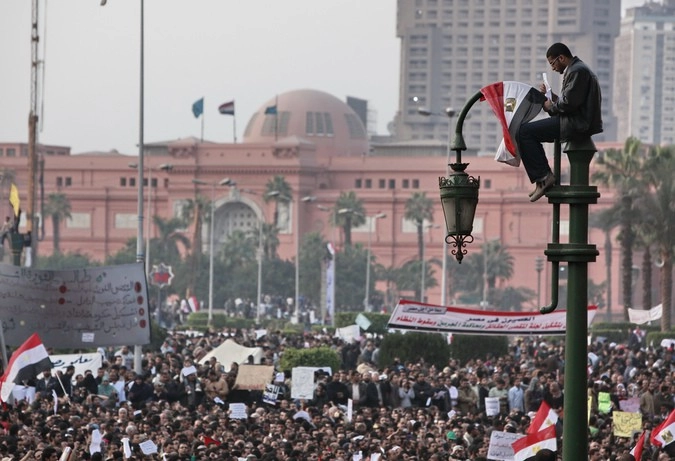 Демонстрант наблюдает за протестующими на центральной площади Каира Тахрир. В Египте проходят массовые акции протеста с требованием реформ и отставки президента Хосни Мубарака.  01.02.2011 